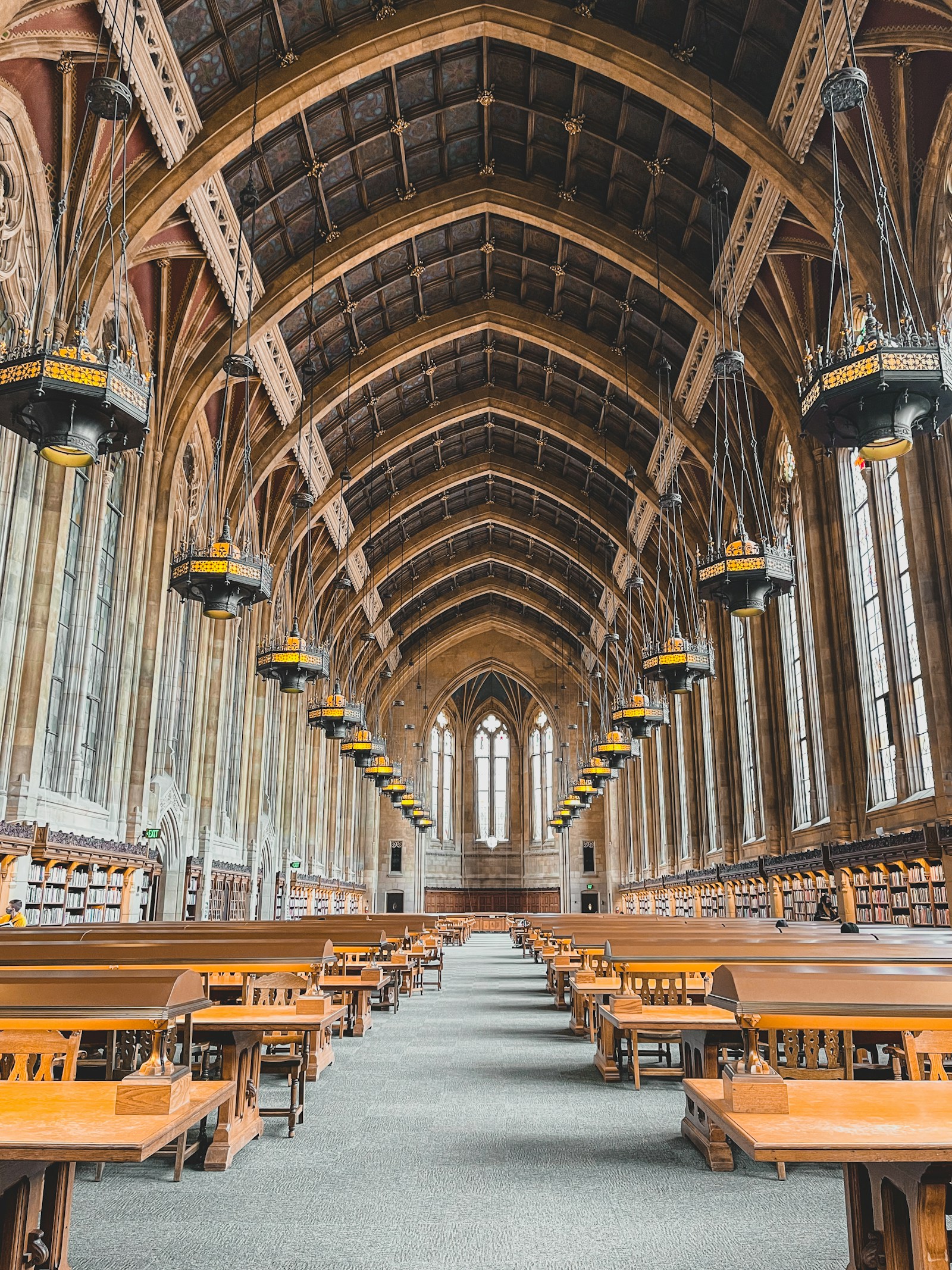 An empty library reading room with long wooden tables and afternoon light