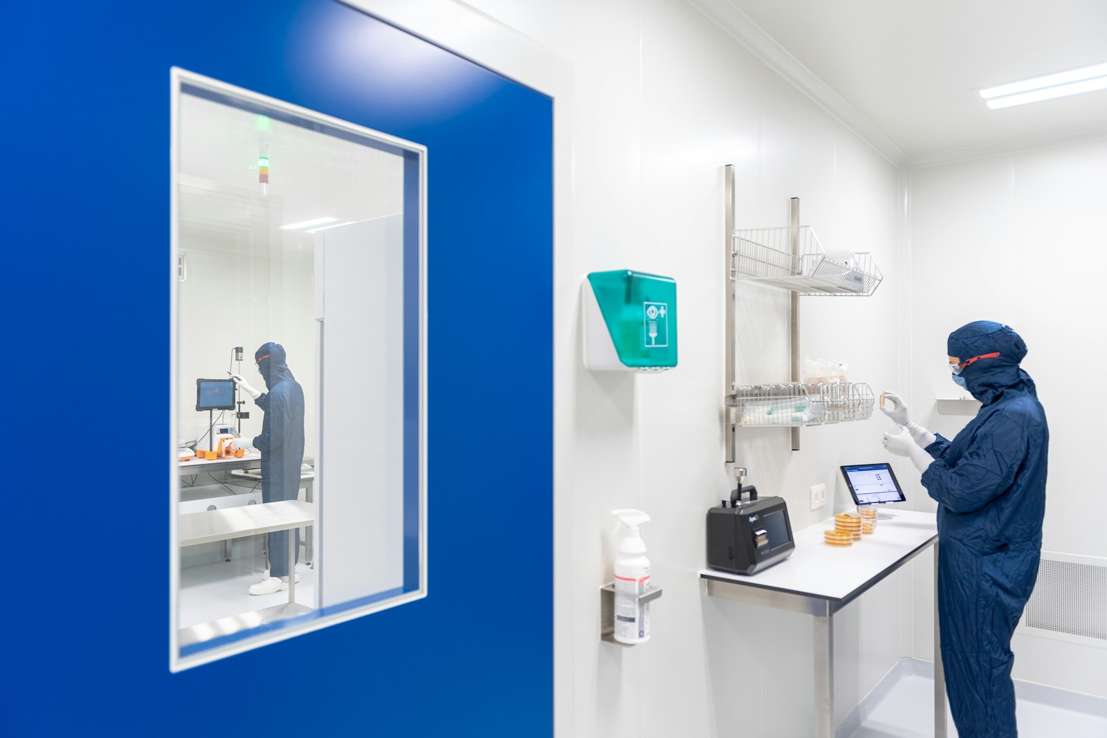 Interior corridor of a semiconductor fabrication cleanroom, lined with tall stainless-steel process tools under cold blue-grey light